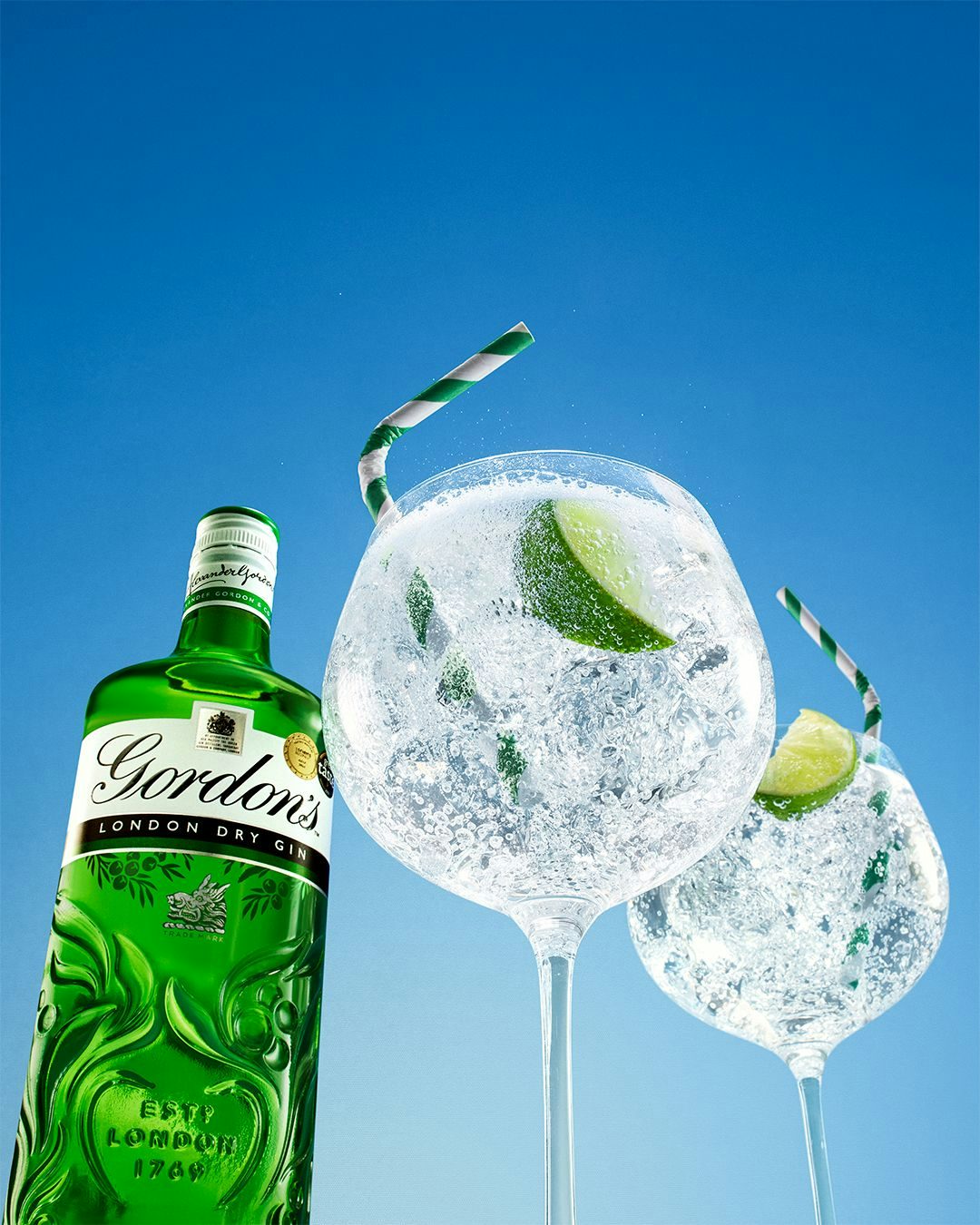 Two cocktails and a Tanqueray Gin bottle seen from a low angle.