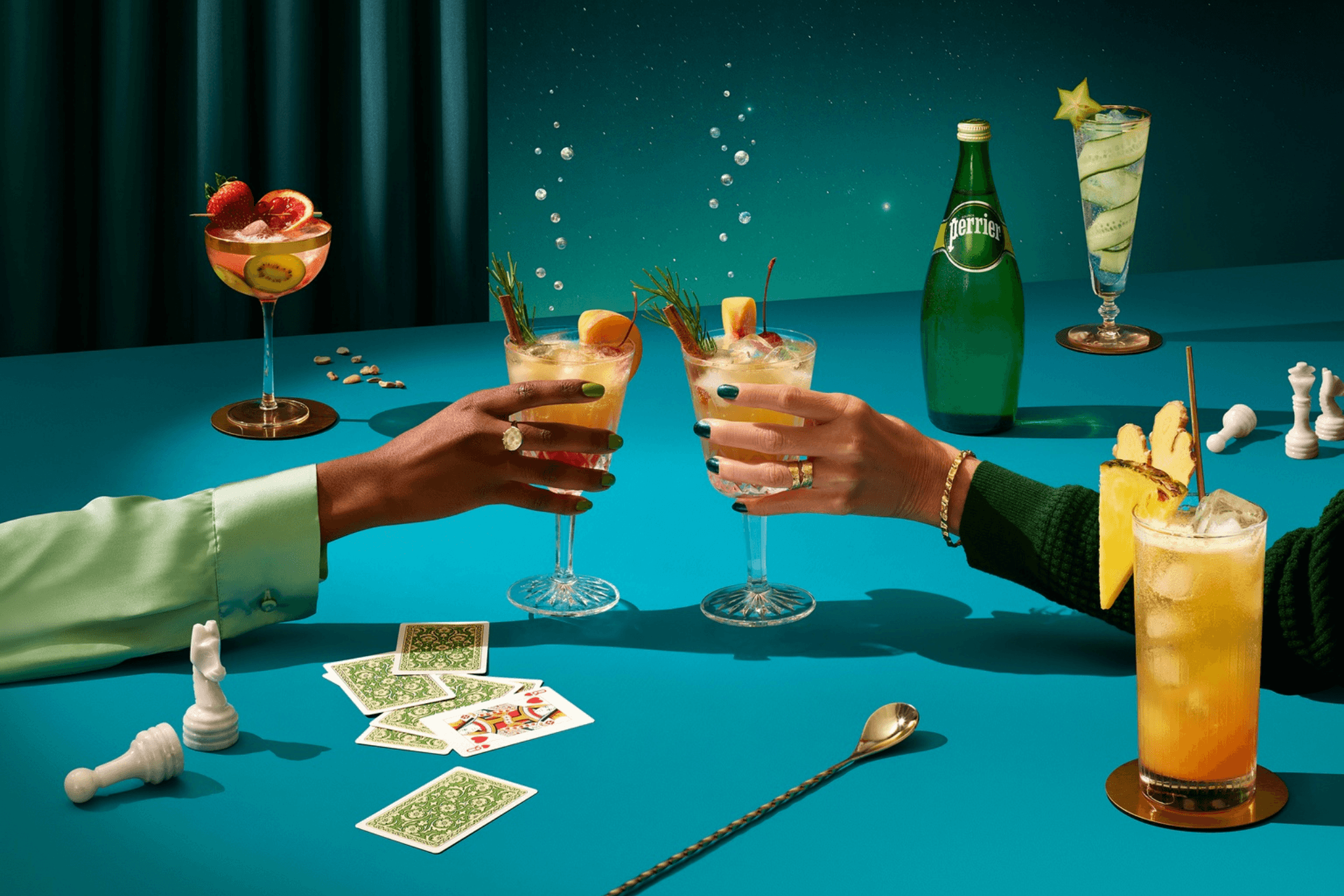 Arms of two people toasting with cocktails over a card game table.